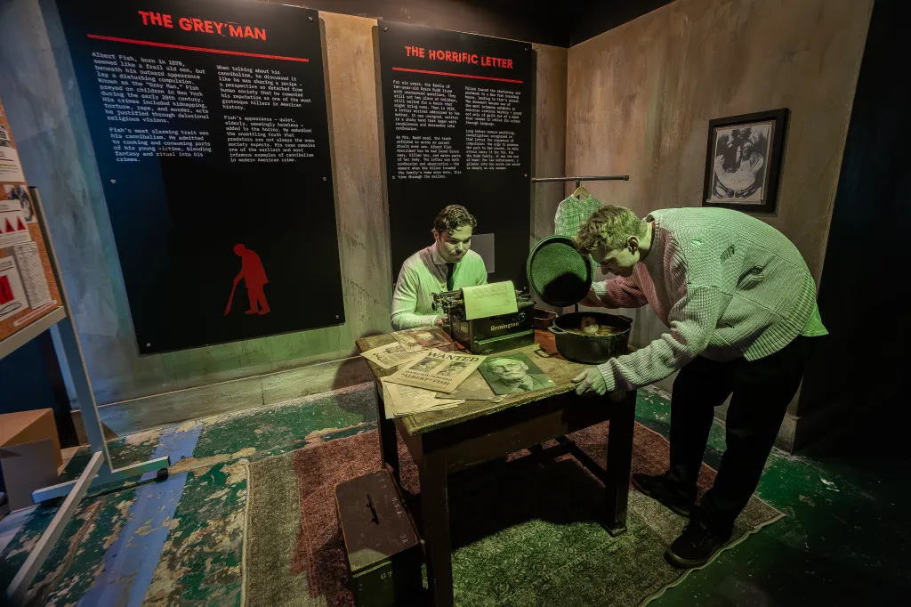 Exhibition with two mannequins, one typing and the other looking into a pot, with informational displays about 