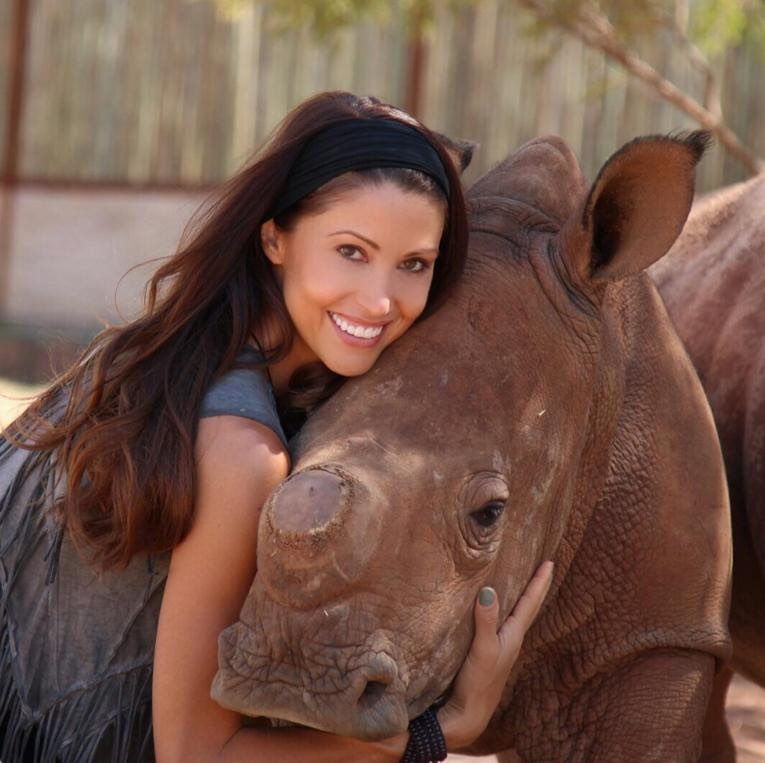 Shannon Elizabeth smiling while embracing a rhino.