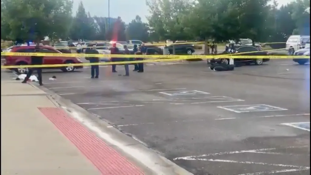 Crime scene with police cars and yellow tape in a parking lot.