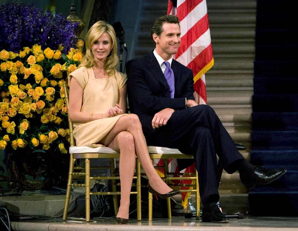 San Francisco Mayor Gavin Newsom and his fiancée Jennifer Siebel sit before his second term swearing-in.