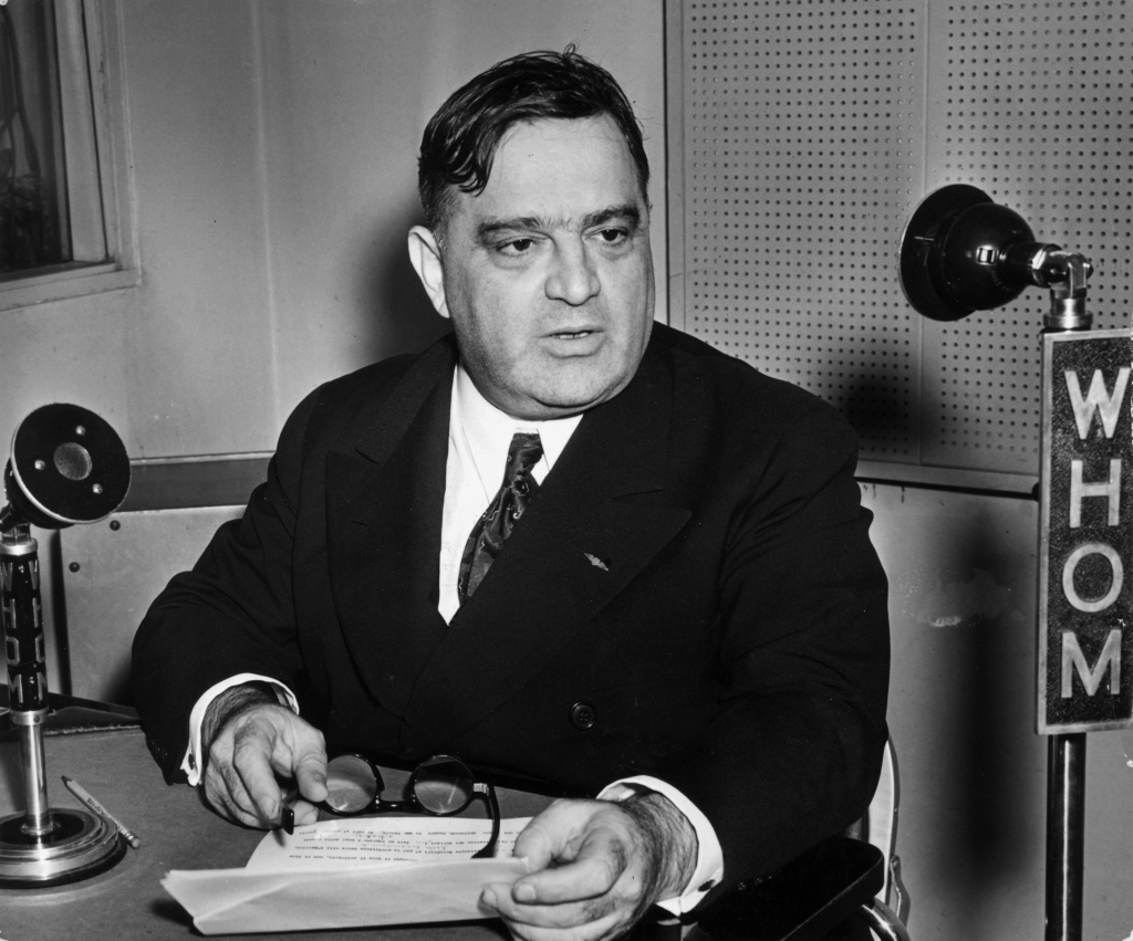 Black and white photo of Fiorello Henry La Guardia at a radio microphone.