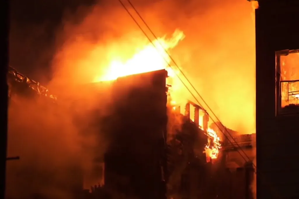 Large fire engulfing several buildings at night.