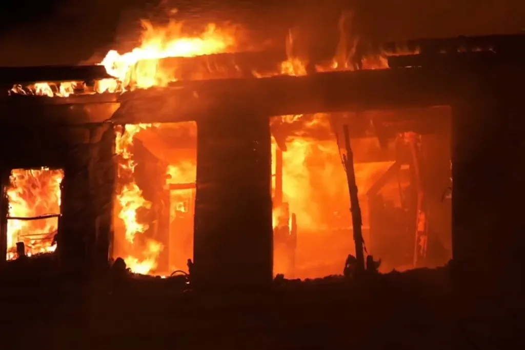 Flames engulfing a building at night.