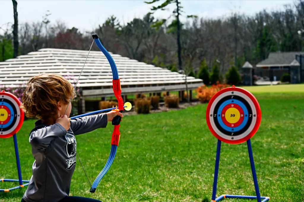 A young boy aiming a toy bow and arrow at a target.