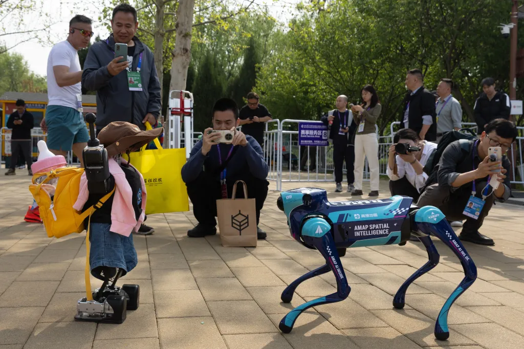 Spectators filming child-like humanoid and dog-like robots at the Beijing E-Town Half Marathon.