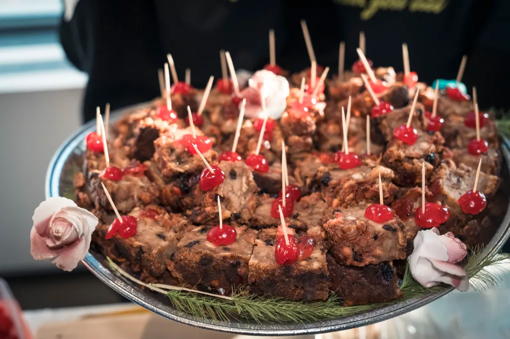 Bread pudding squares with maraschino cherries on a silver tray.