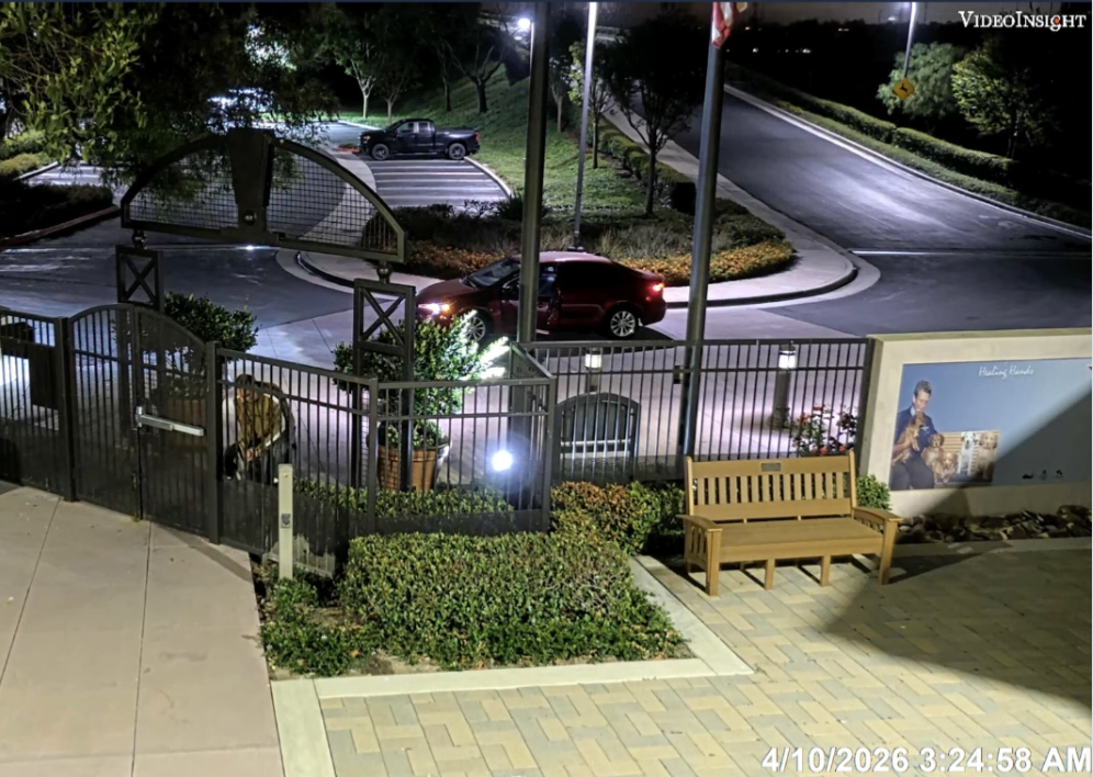 A person throwing a puppy over a fence at an animal shelter at night.