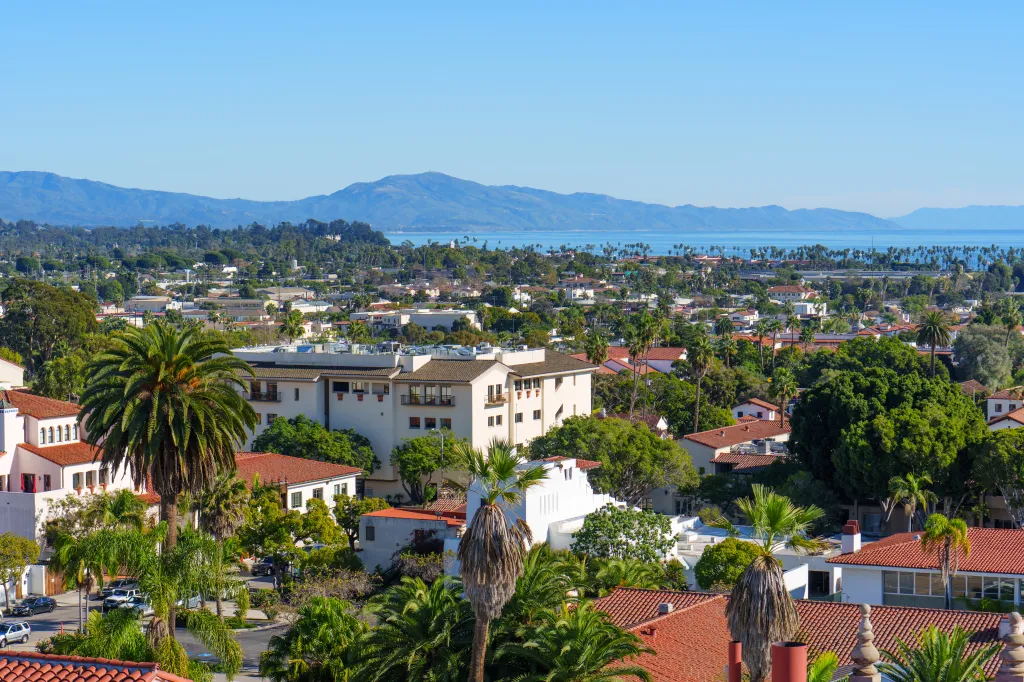 High-angle panorama of Santa Barbara, showing the city, palm trees, and the Pacific Ocean.