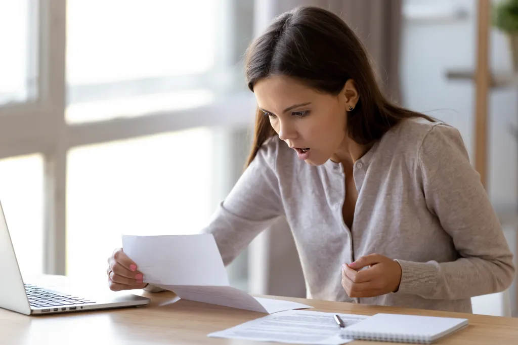 Surprised young woman reading a letter.