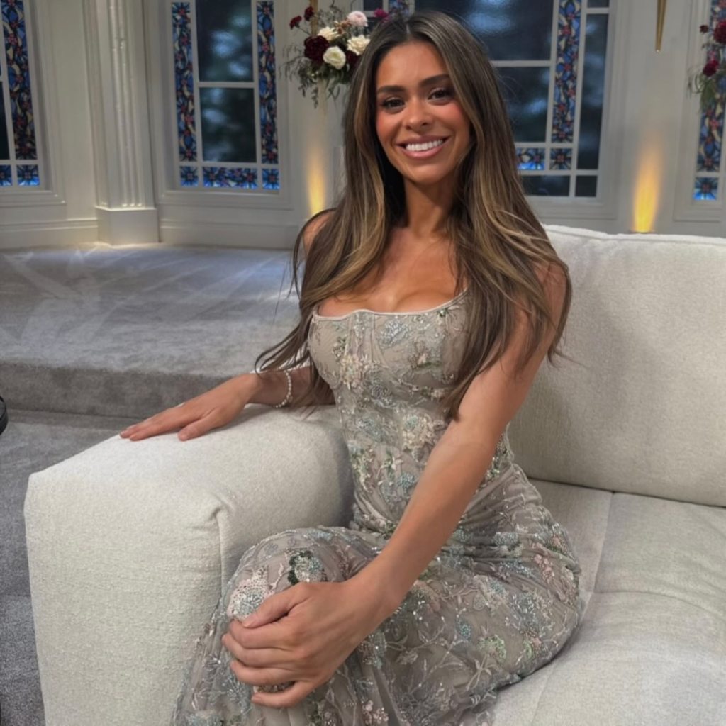 Taylor Frankie Paul sitting on a white sofa in a long, embroidered dress.