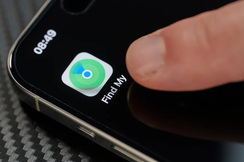 Finger touching the Find My app icon on an iPhone screen.