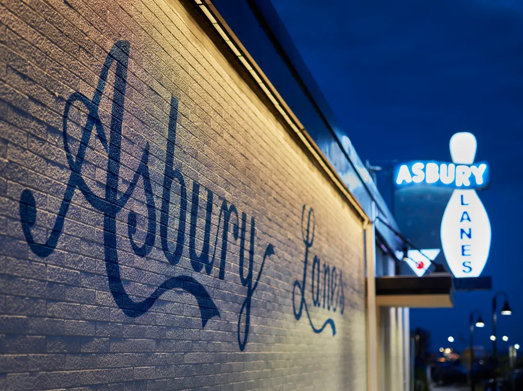 The exterior of Asbury Lanes at the Asbury Hotel at night, with 