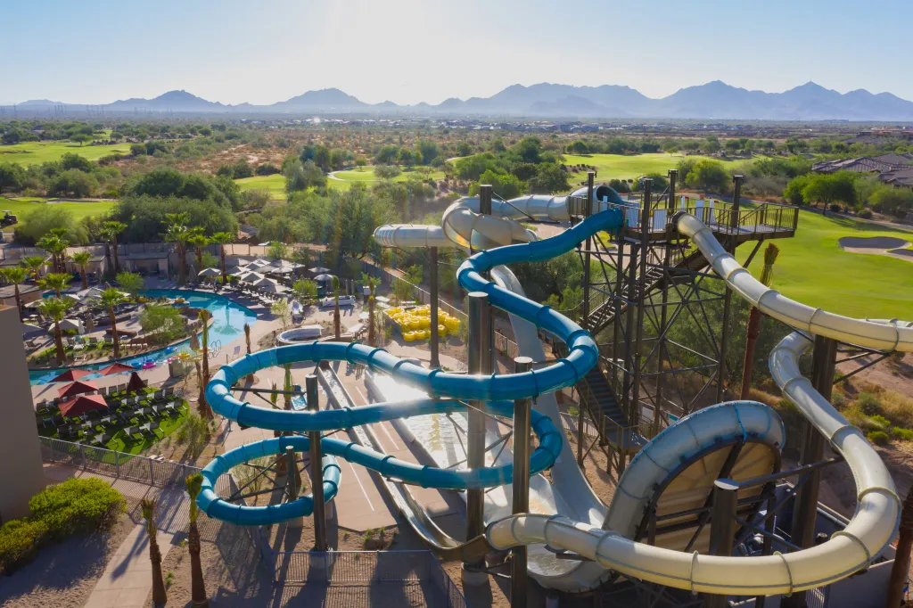 The AQUARIDGE Waterpark at JW Marriott Phoenix Desert Ridge Resort & Spa features multiple waterslides with golf courses and mountains in the background.
