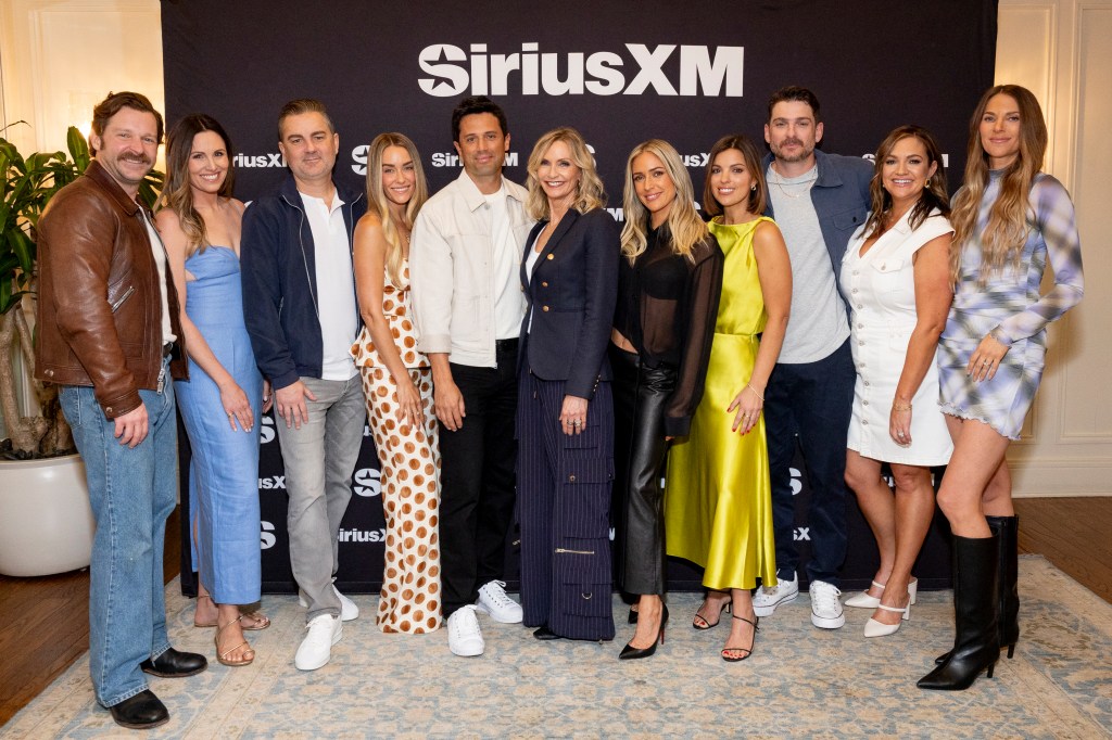 The cast of Laguna Beach pose for a photo in front of a black backdrop with the SiriusXM logo.