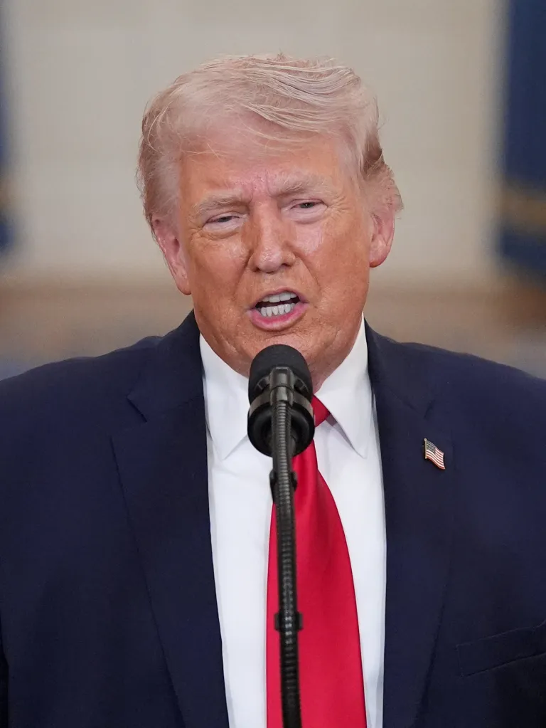 U.S. President Donald Trump speaks into a microphone from a podium.