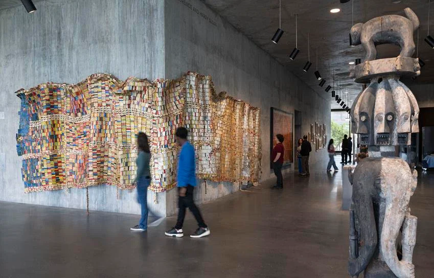 Textile Conversations: Africa and Black America installation view featuring El Anatsui's Fading Scroll, 2007, left, and an Ijo Republic of Nigeria Forest Spirit Figure, early 19th century. Source: Museum Associates/LACMA