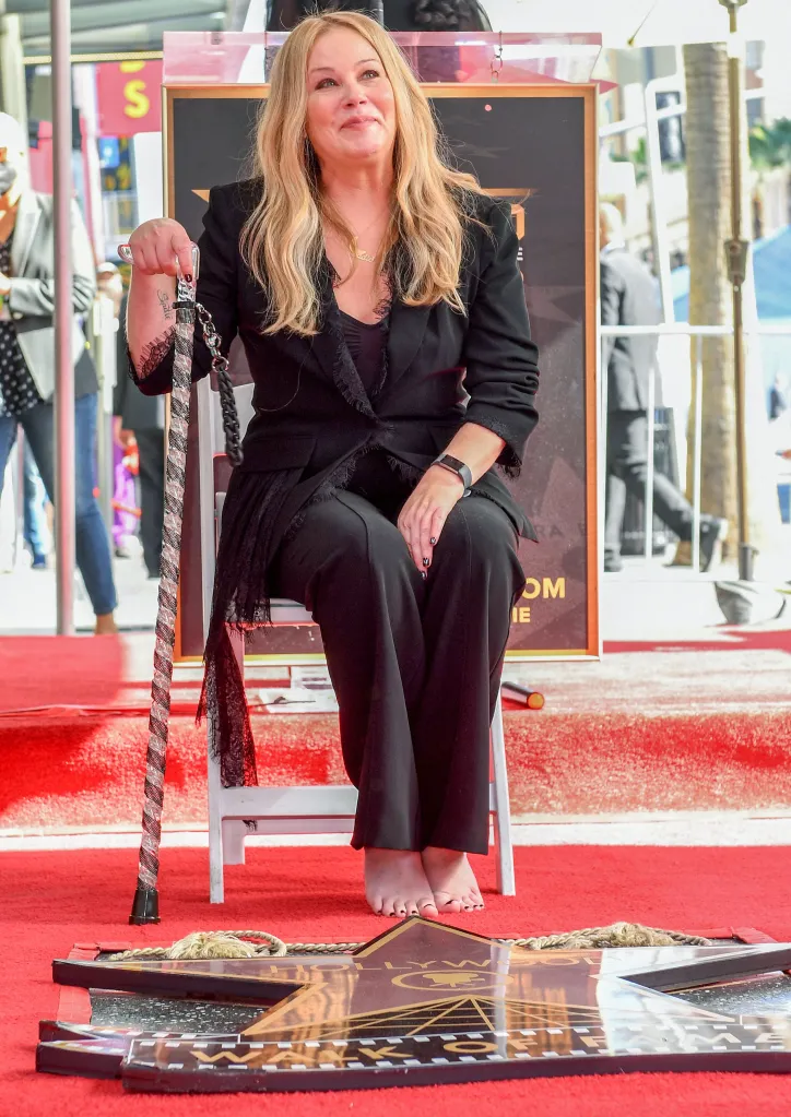 Actress Christina Applegate seated on a white chair, holding a cane, at her Hollywood Walk of Fame star ceremony.