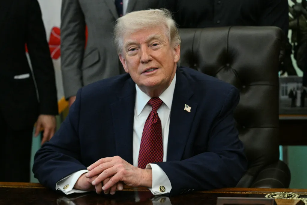 US President Donald Trump seated at a desk after signing an executive order.