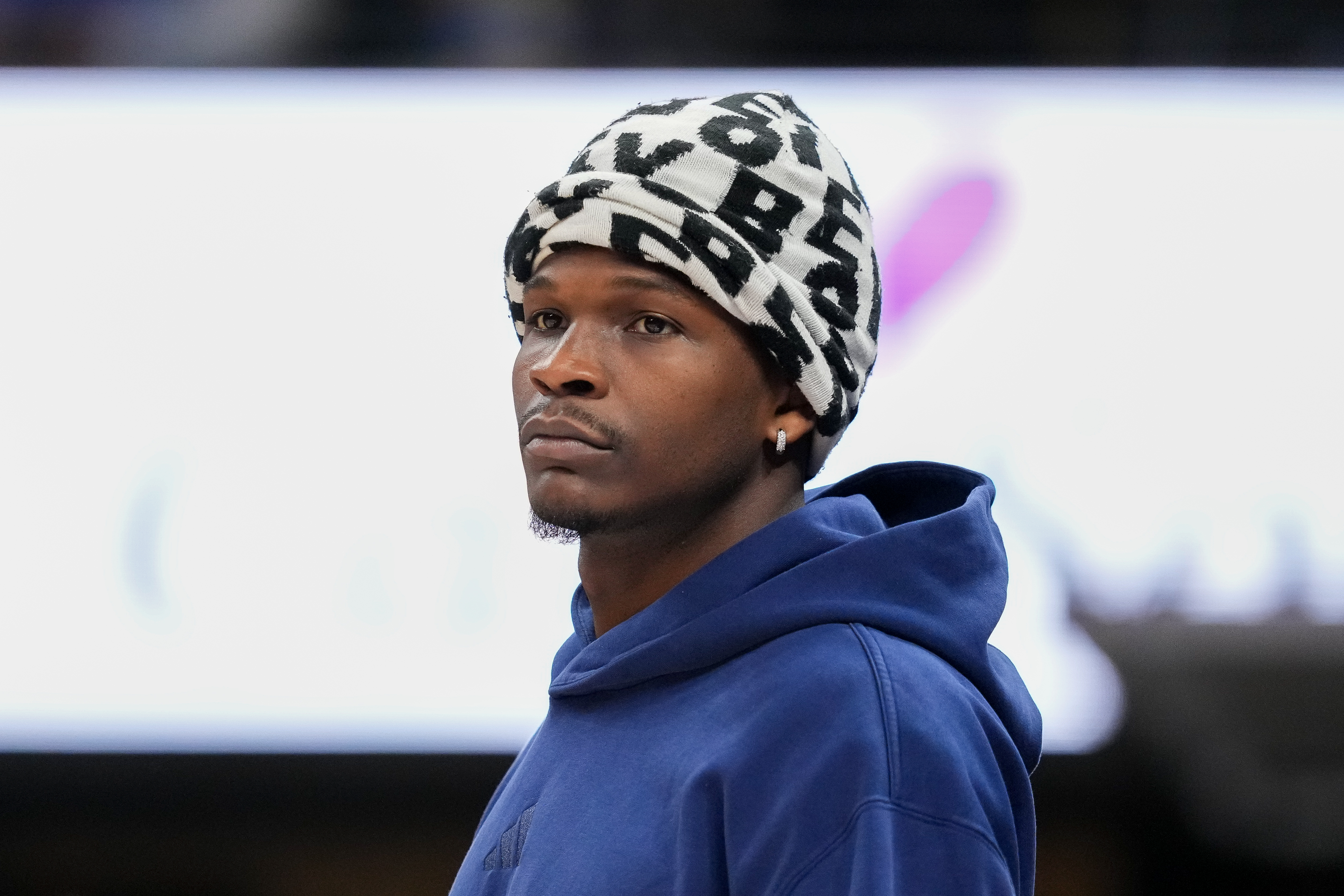 Anthony Edwards wearing a black and white patterned beanie and blue hoodie, looking to the right.