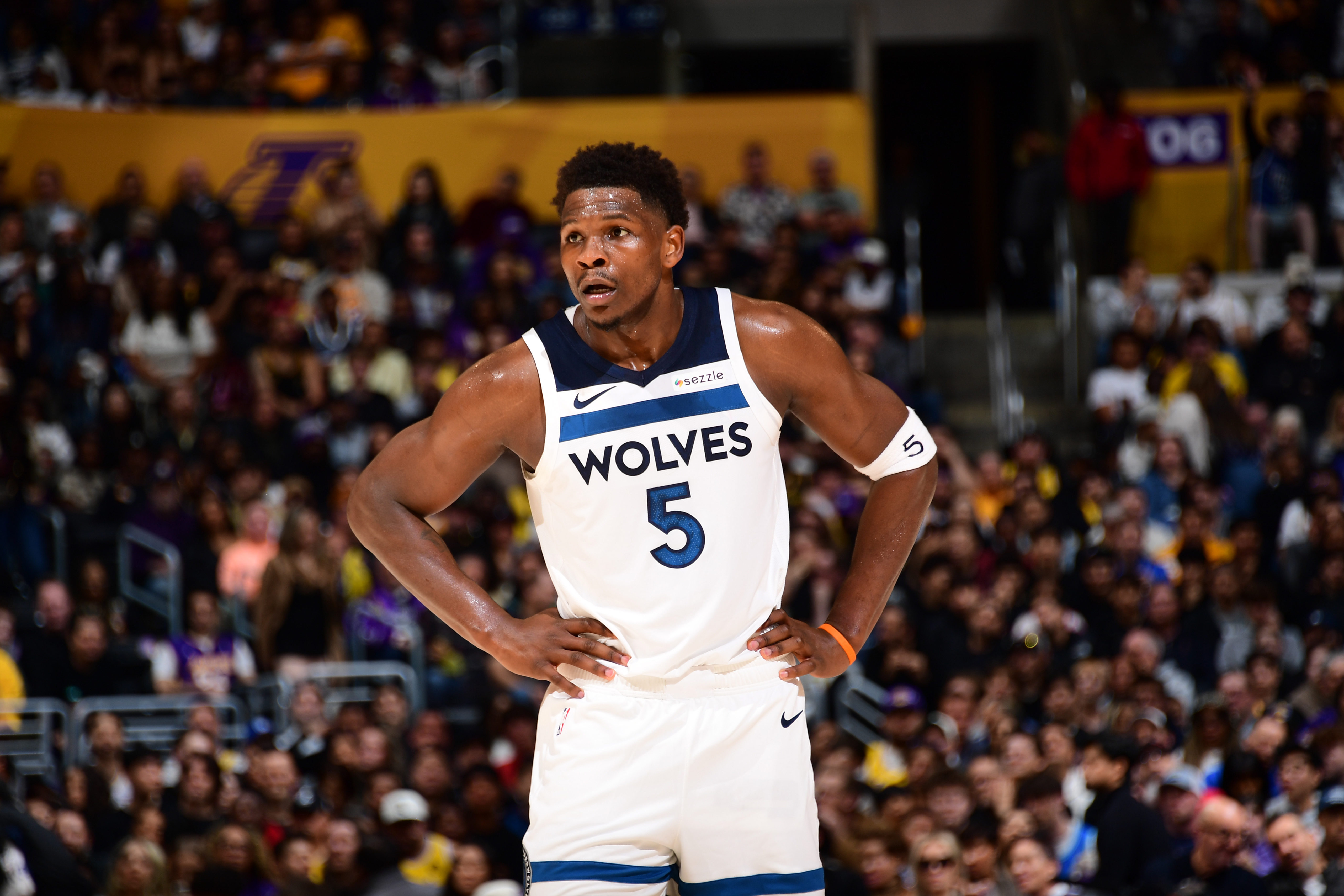 Anthony Edwards in a white Timberwolves jersey with number 5 and the Sezzle logo, looking intently while playing basketball.