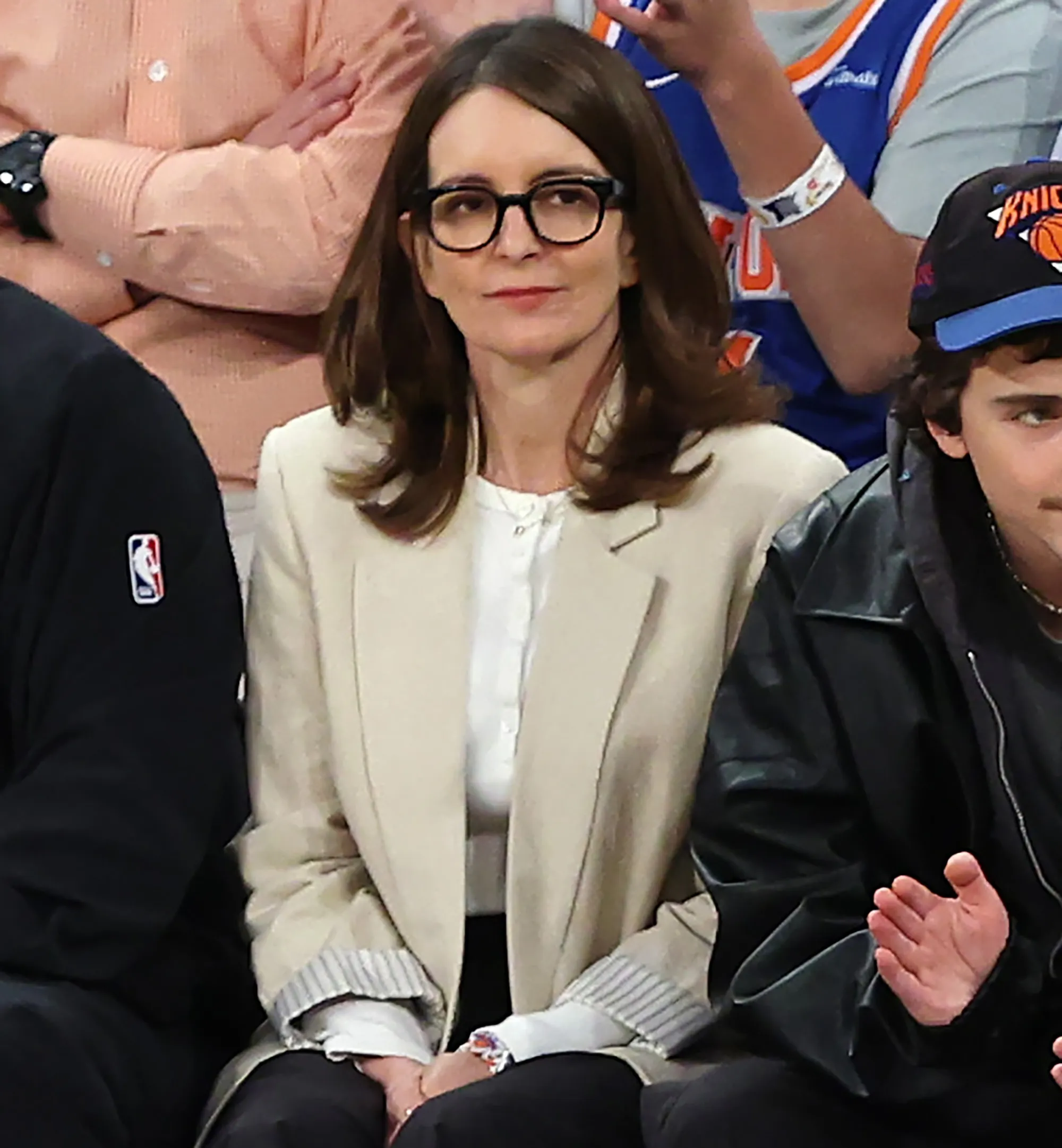 Tina Fey watches a basketball game from the stands.