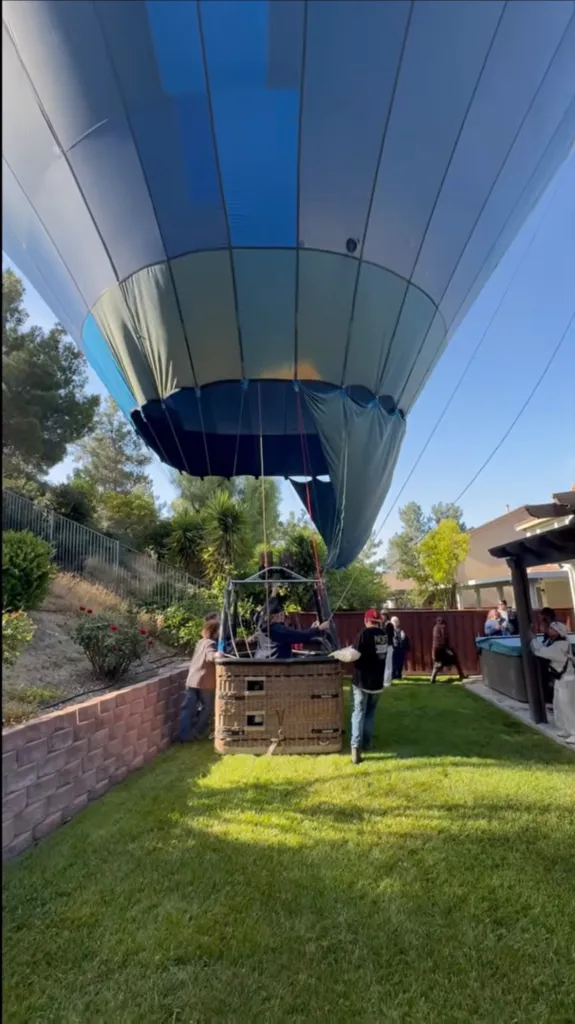 Hot air balloon making an emergency landing in a backyard.