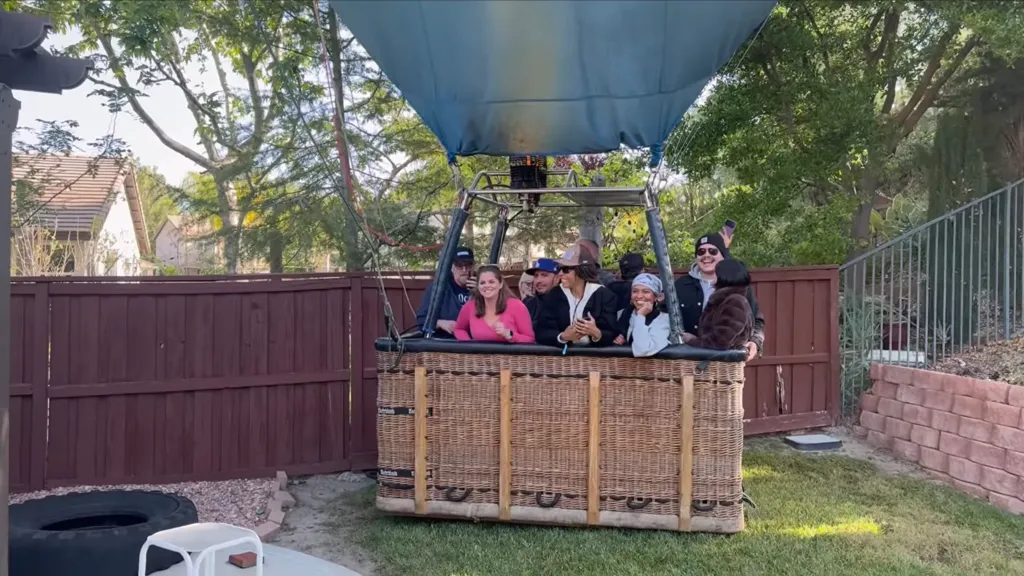 A group of people in a hot air balloon basket landed in a backyard.