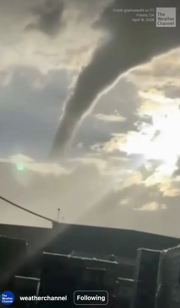 A funnel cloud descends from a cloudy sky.