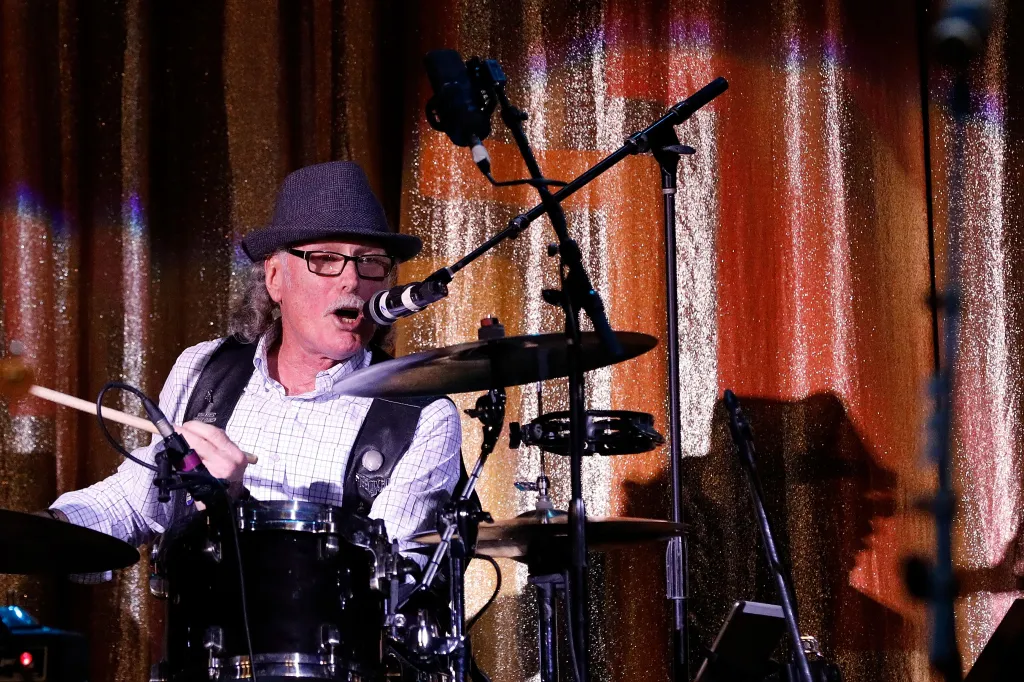 Vini Lopez playing drums and singing into a microphone.