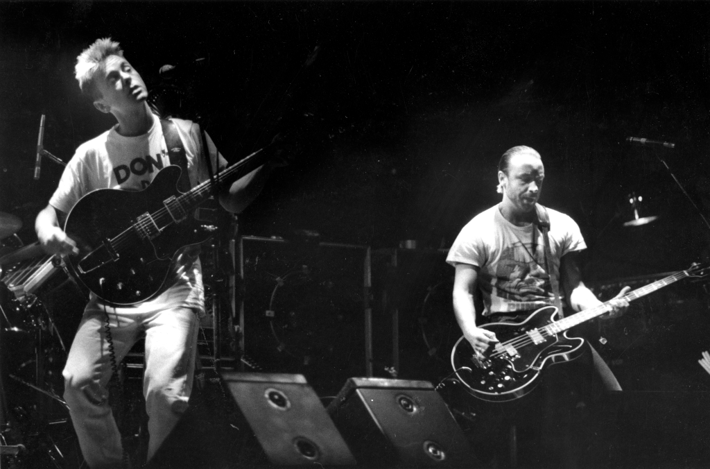 Bernard Sumner and Peter Hook of New Order performing on stage.