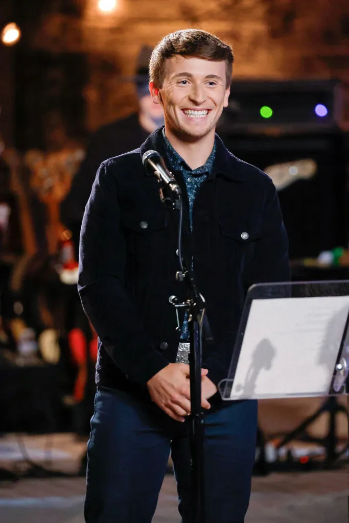 Dylan Carter smiling while standing at a microphone stand.