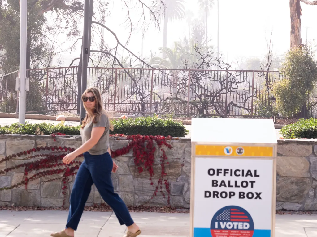 A voter walks past an official ballot drop box in the fire-devastated Pacific Palisades district.