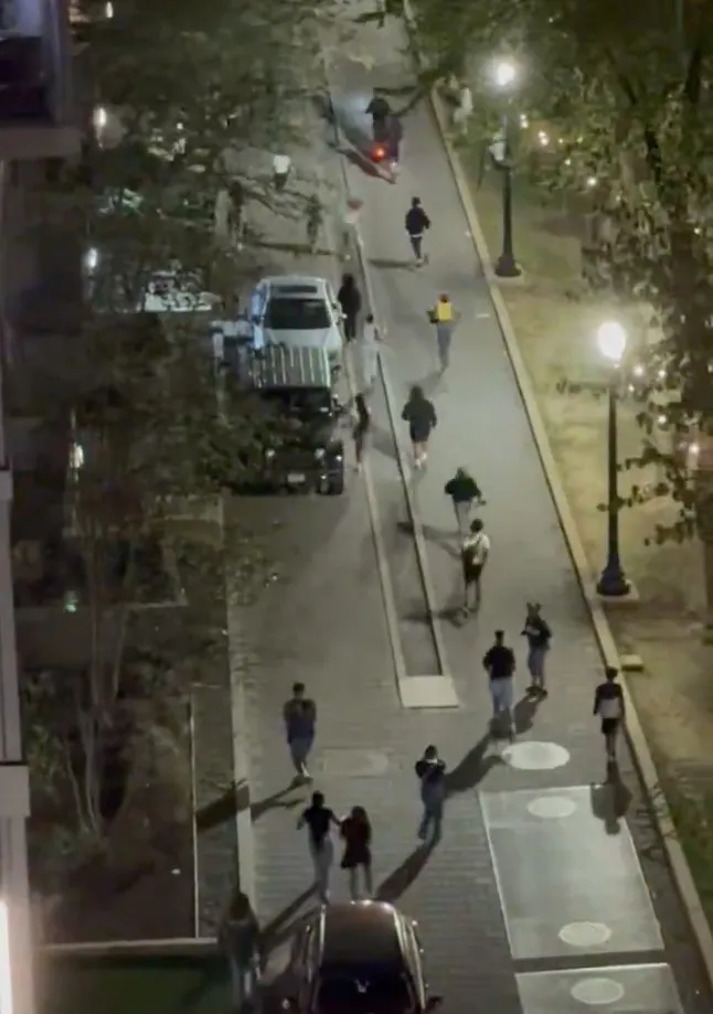Overhead view of a street at night with people running and on scooters.