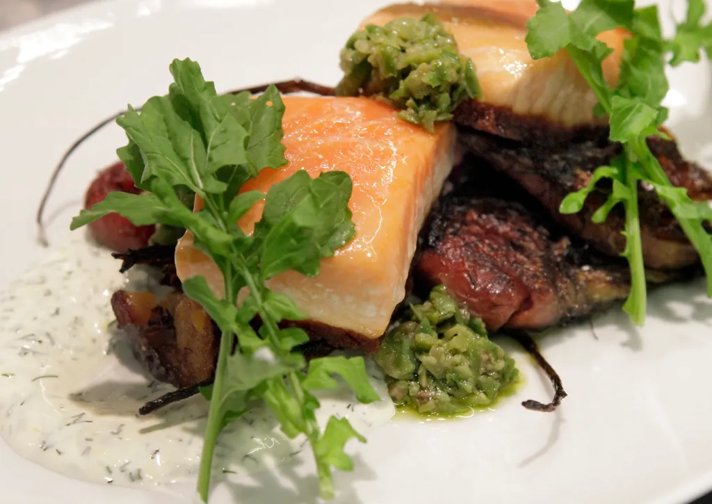 Wild King Salmon dish with a side of greens and sauces.