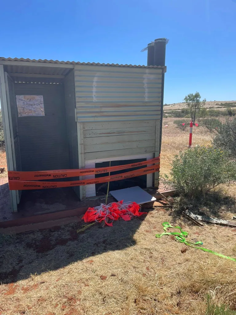 An outdoor toilet structure with a missing bottom portion and 