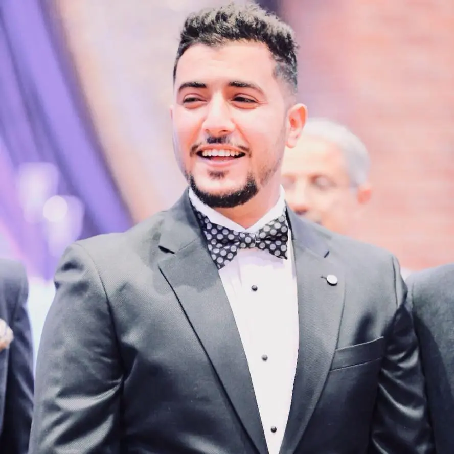 Abdulmalek Anwar wearing a black suit and a polka dot bow tie.
