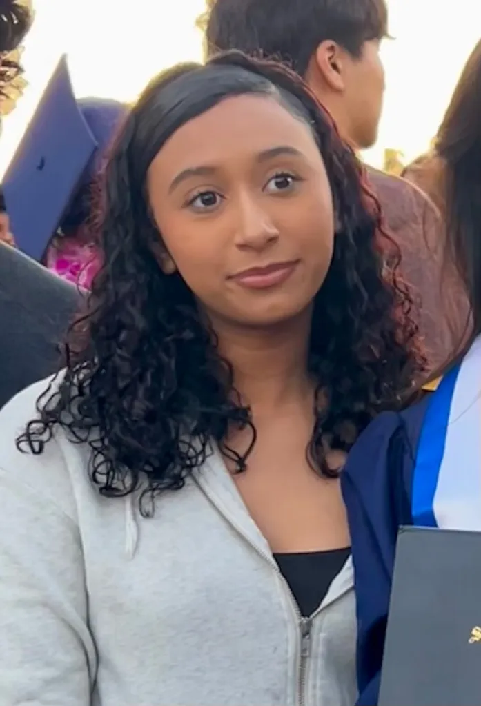 Celeste Rivas Hernandez with dark curly hair and a light-colored hoodie, looking slightly to the right.