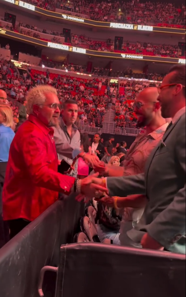 Guy Fieri shaking hands with men in a stadium.