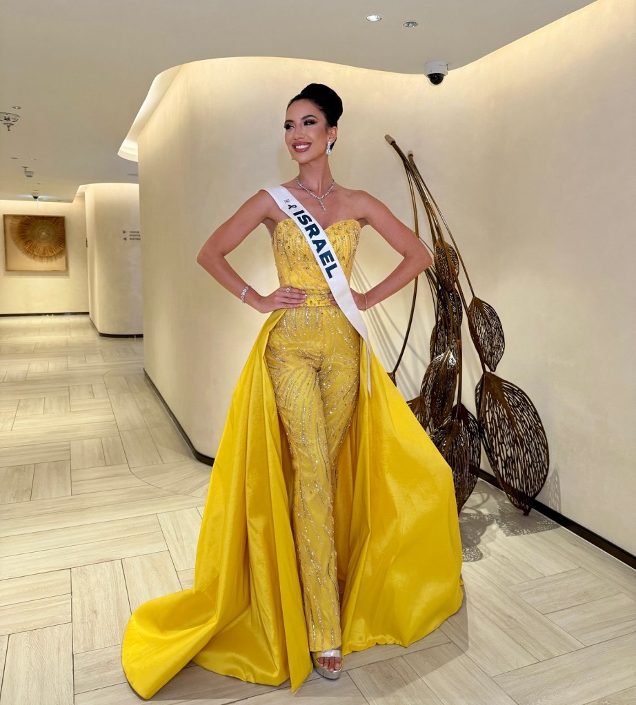 Melanie Shiraz Asor in a yellow jeweled jumpsuit with a long yellow train and 