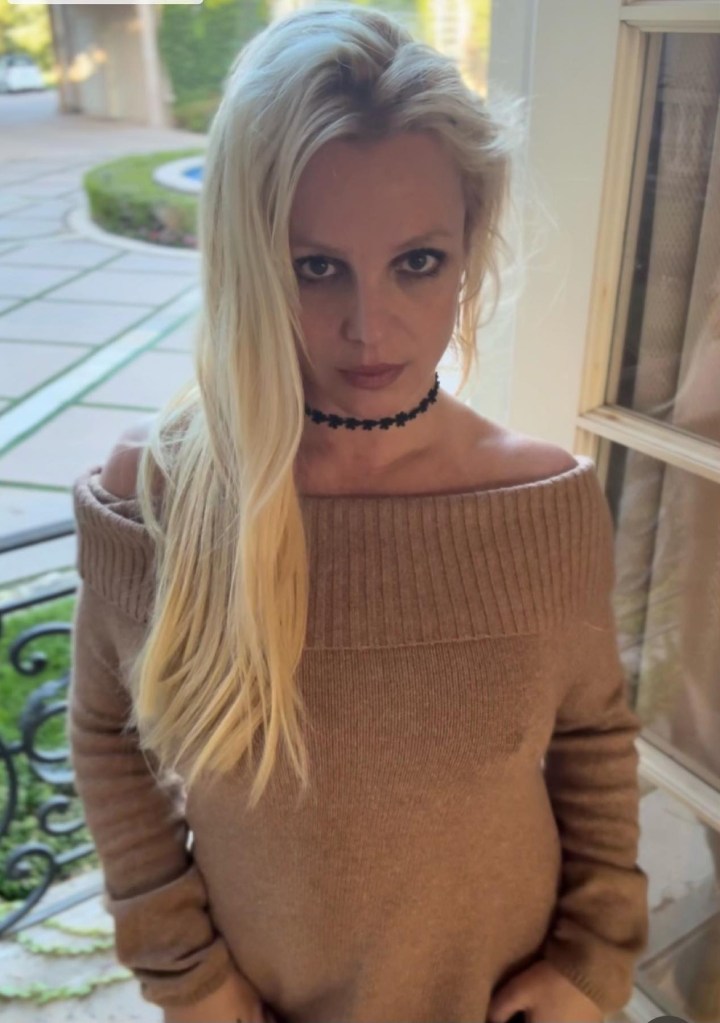Britney Spears wearing a beige off-the-shoulder sweater and a black floral choker.