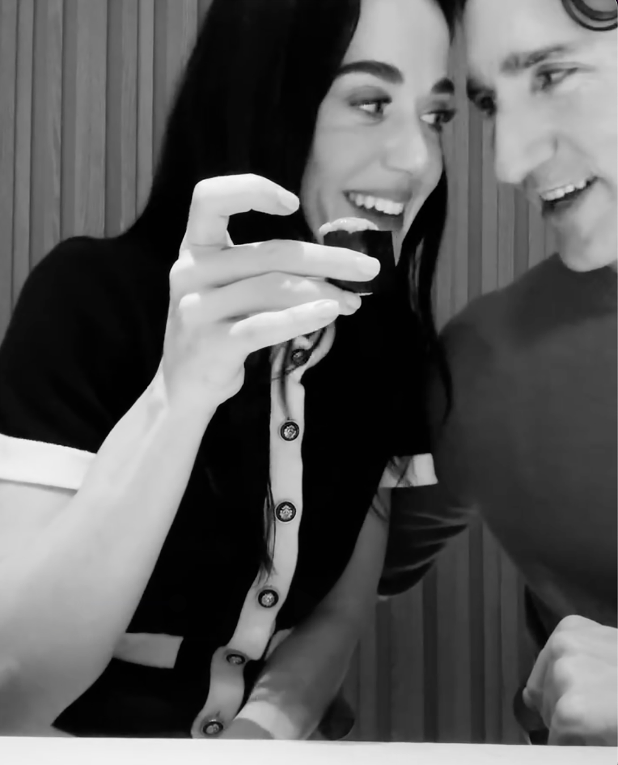 Black and white photo of Katy Perry holding sushi near Justin Trudeau's face.