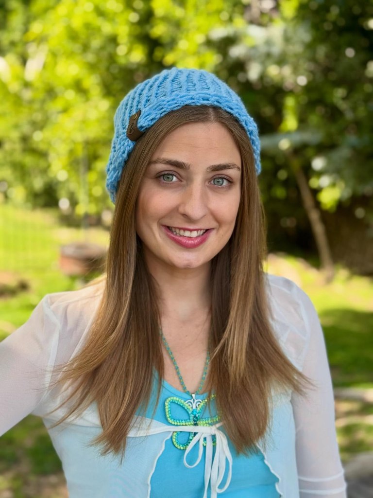 Portrait of Abbey Romeo wearing a light blue beanie and a blue top.