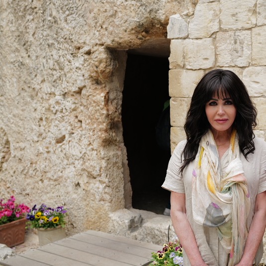 Marie Osmond stands in front of a stone tomb.