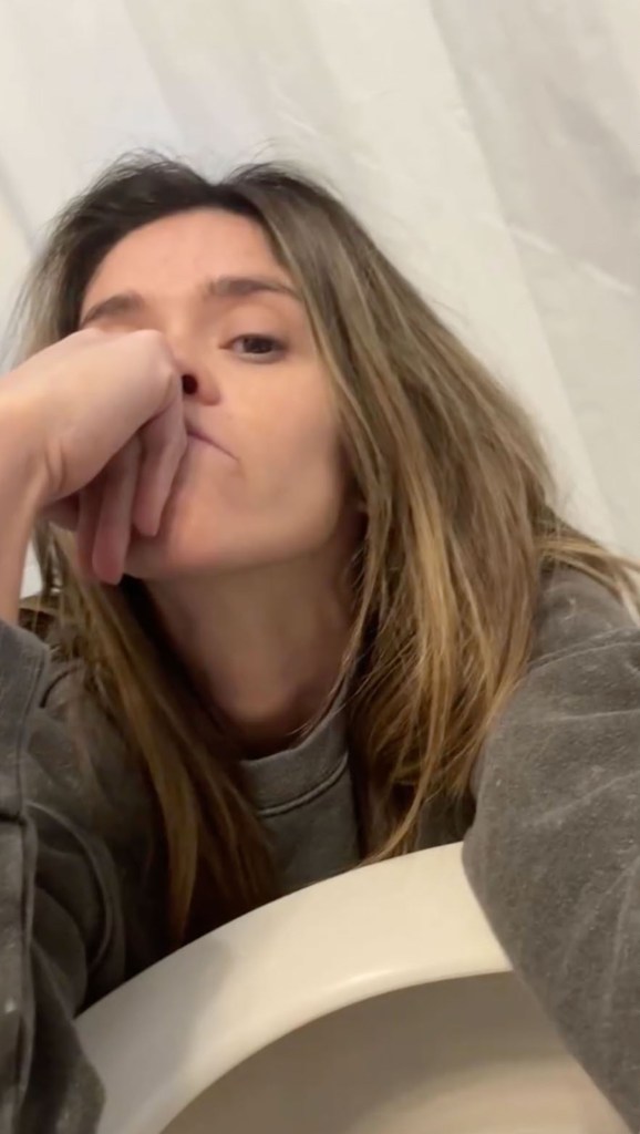 A woman with brown hair rests her head on her hand, looking exhausted.