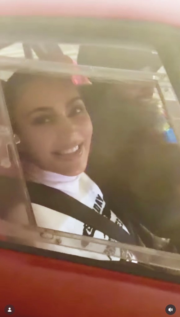 Woman in a car, seen through the window, smiling.