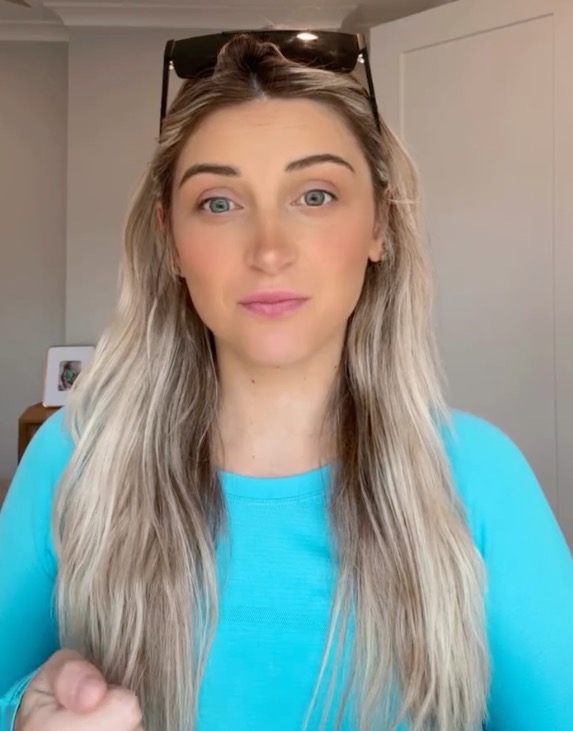 A woman with long blonde hair and sunglasses on her head.