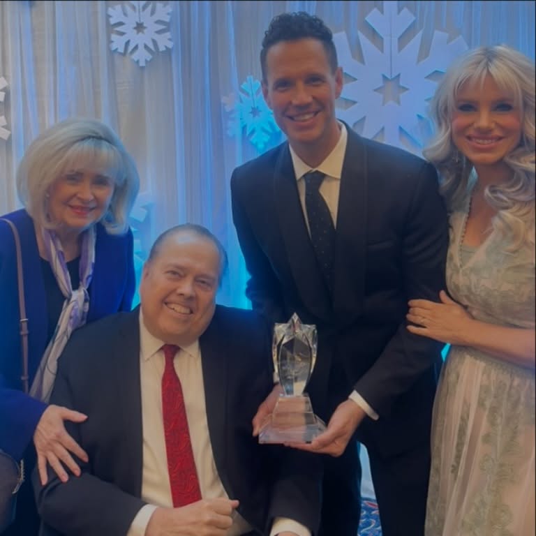 Alan Osmond and his son with their family holding an award.