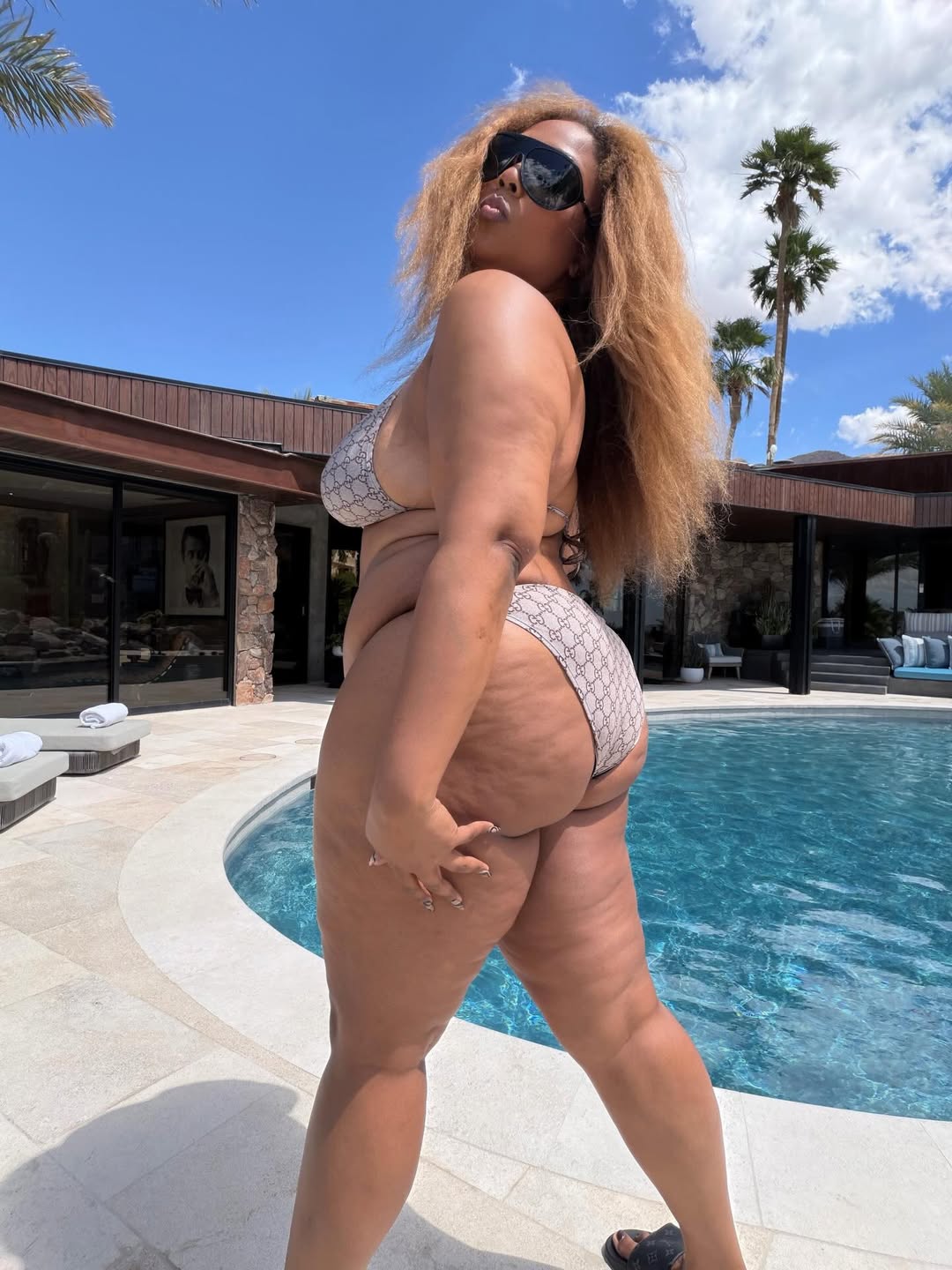 Lizzo posing in a Gucci bikini by a pool.