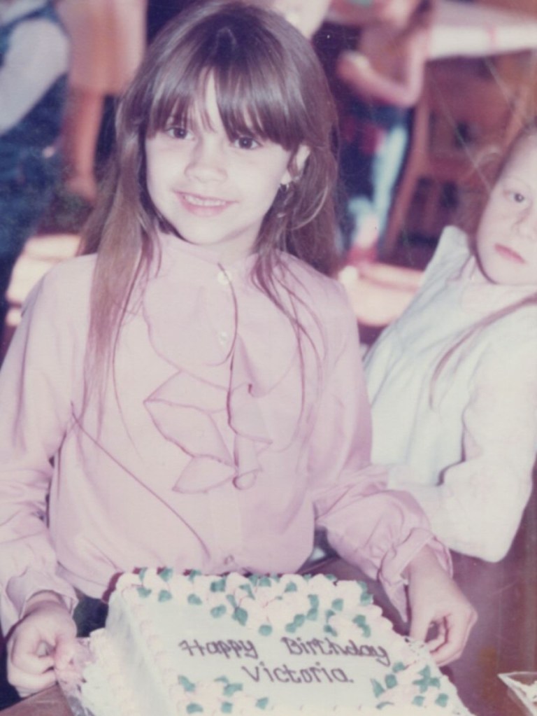 A young Victoria Beckham smiles over a 