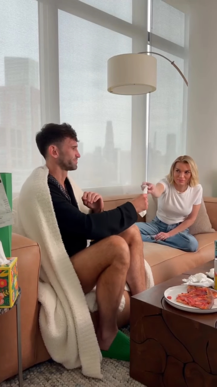 Lindsay Hubbard passing tissues to Carl Radke, who is wrapped in a blanket on a couch.